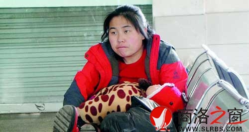 候車廳里，一位母親抱著睡著的孩子發呆